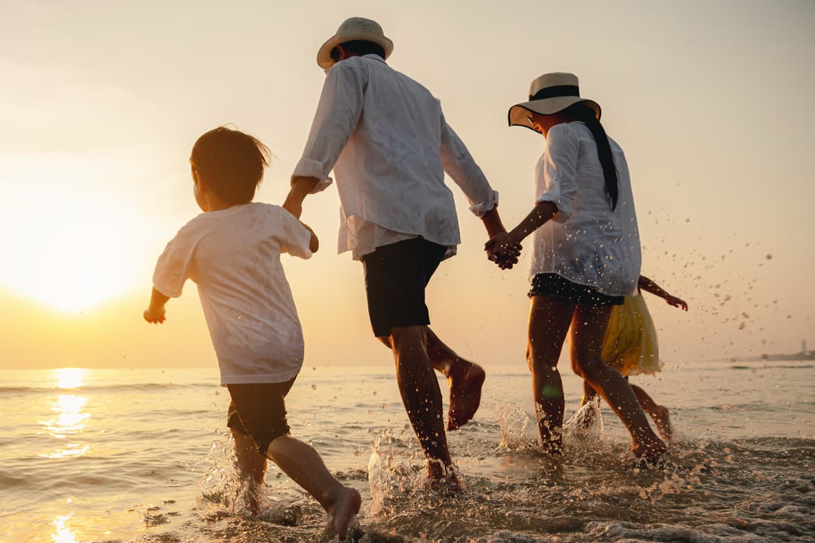 A family of three walking together on a shoreline.